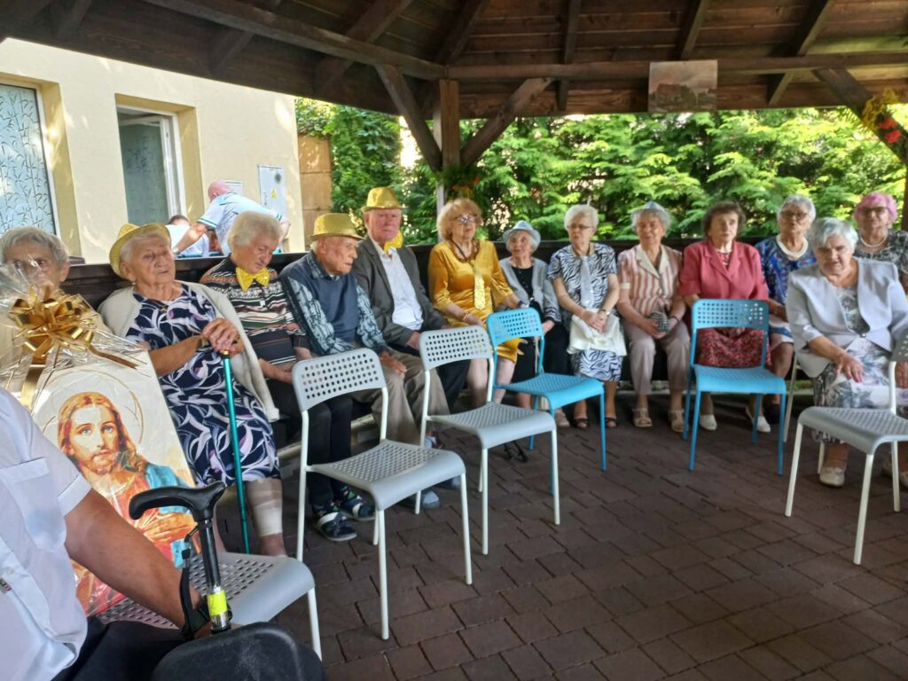 Na zdjęciu widzimy siedzących w altance ogrodowej mieszkańców domu seniora