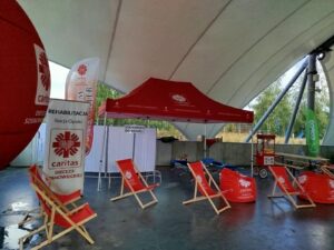 na zdjęciu widzimy leżaki z logiem Caritas oraz baner reklamowy Caritas